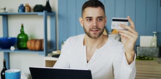 Man holding credit card while looking at laptop
