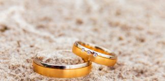 two gold wedding rings laying on the sand