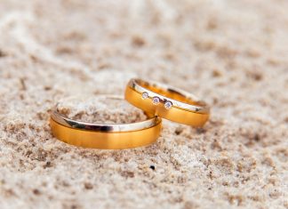 two gold wedding rings laying on the sand