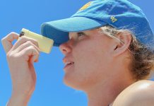 a woman wearing a blue hat looking through a magnifying glass