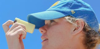 a woman wearing a blue hat looking through a magnifying glass