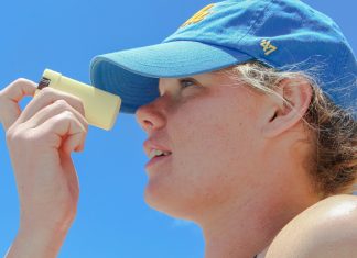 a woman wearing a blue hat looking through a magnifying glass