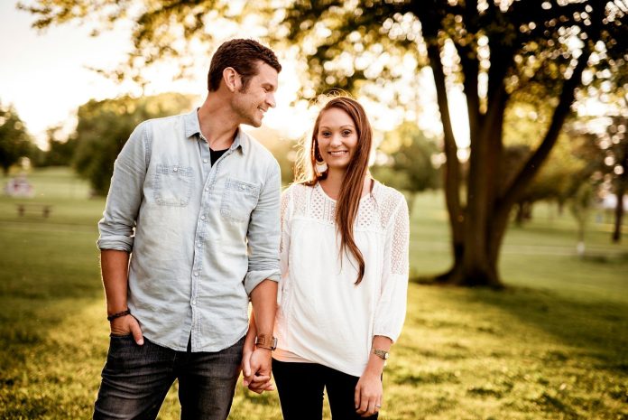 Photo by Ben White man holding hand of woman standing near tree