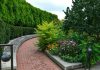 How Landscape Construction Increases Property Value a brick path with a garden of flowers and trees