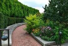 a brick path with a garden of flowers and trees
