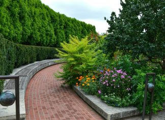 How Landscape Construction Increases Property Value a brick path with a garden of flowers and trees