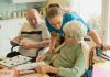 What Different Levels of Care in Assisted Living Actually Mean Caregiver assisting elderly couple with coloring