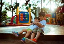 How ABA Services for Children Target Specific Behavioral Goals boy carrying child while sitting on gray concrete platform