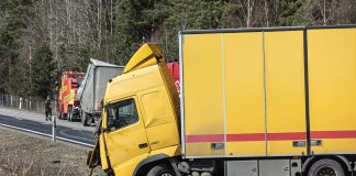 A yellow semi-truck is in a roadside accident.