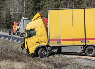 A yellow semi-truck is in a roadside accident.
