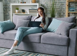 How Technology Is Quietly Rewriting the Rules of Modern Living Woman wearing headphones uses tablet on couch.