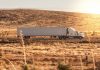a white semi truck driving down a rural road
