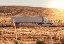 a white semi truck driving down a rural road