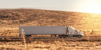 a white semi truck driving down a rural road