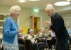 Elderly couple dancing with others watching