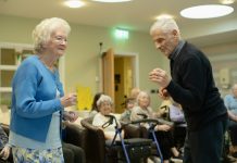 Elderly couple dancing with others watching