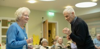 Elderly couple dancing with others watching