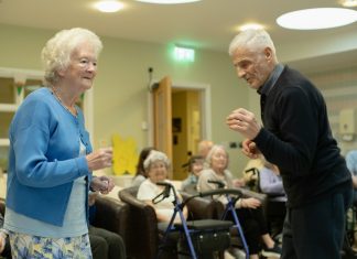 Elderly couple dancing with others watching