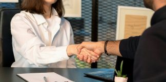 a man and a woman shaking hands in front of a laptop