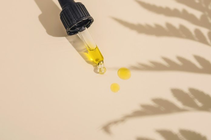 Photo by CRYSTALWEED cannabis a dropper bottle filled with yellow liquid sitting on top of a table