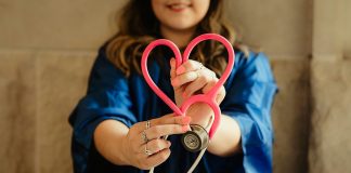 woman in scrubs holding heart shaped stethoscope