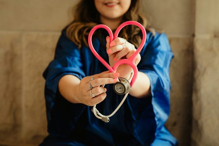 Photo by Patty Brito woman in scrubs holding heart shaped stethoscope