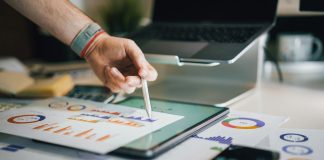 person using stylus on tablet with charts