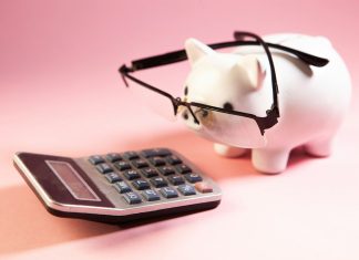 A piggy bank wearing glasses next to a calculator