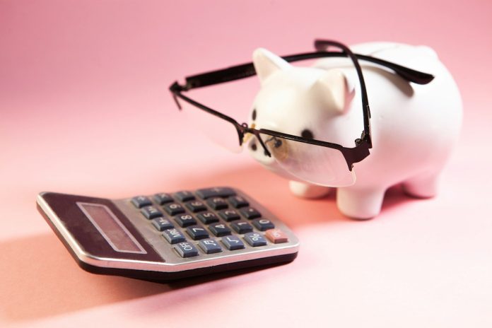 Photo by Sasun Bughdaryan A piggy bank wearing glasses next to a calculator