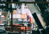 A man in a grey and red shirt operating industrial machinery in a factory