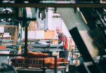 A man in a grey and red shirt operating industrial machinery in a factory