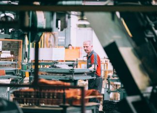 A man in a grey and red shirt operating industrial machinery in a factory
