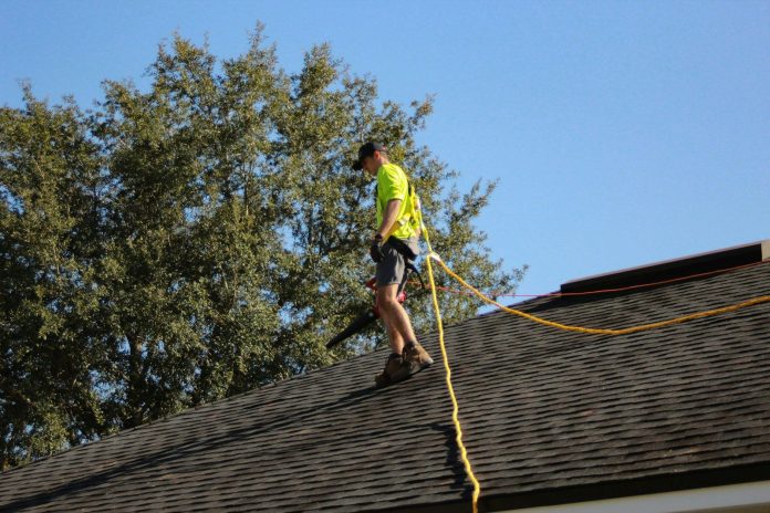 Photo by Raze Solar a man on a roof working with a rope