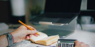 a person sitting at a desk with a calculator and a notebook