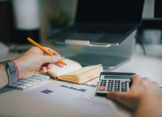 a person sitting at a desk with a calculator and a notebook