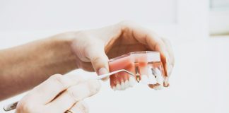 person wearing silver-colored ring while holding denture