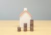 a house and stacks of coins on a table