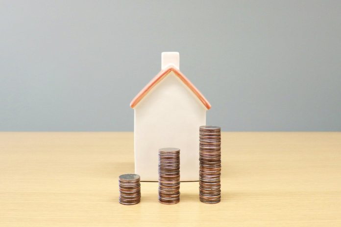 Photo by Artful Homes a house and stacks of coins on a table