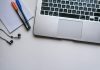 silver laptop computer beside white ruled paper