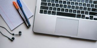 silver laptop computer beside white ruled paper