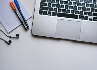 silver laptop computer beside white ruled paper