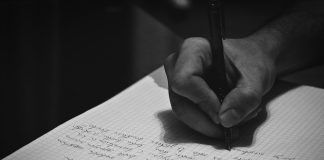 A person writing on a notebook with a pen