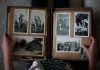 person opening photo album displaying grayscale photos