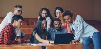 Diverse group of students gathered around laptop