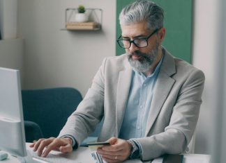 A man sitting at a desk using a laptop computer