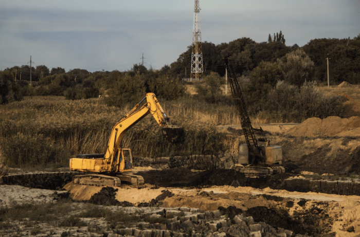 Excavator and crane working exposed soil on a graded job site