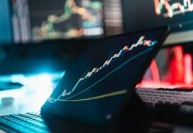 A tablet displaying a rising stock market graph on a desk with a keyboard