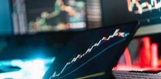 A tablet displaying a rising stock market graph on a desk with a keyboard
