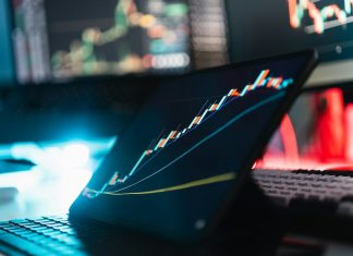 A tablet displaying a rising stock market graph on a desk with a keyboard