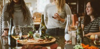 two woman standing beside woman sitting in front of table